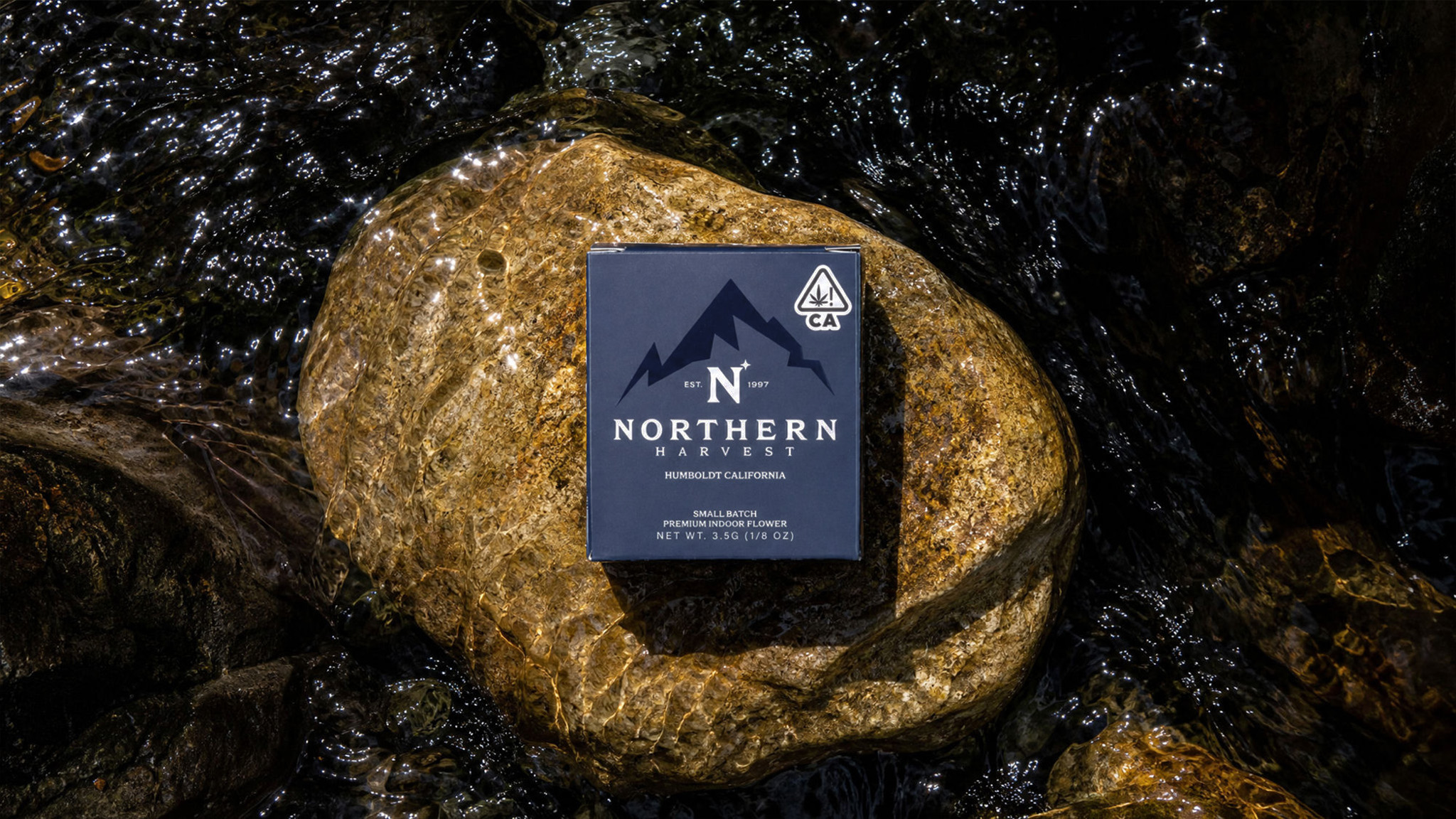 Northern Harvest 3.5g premium indoor flower box on a wet river rock in Humboldt, California